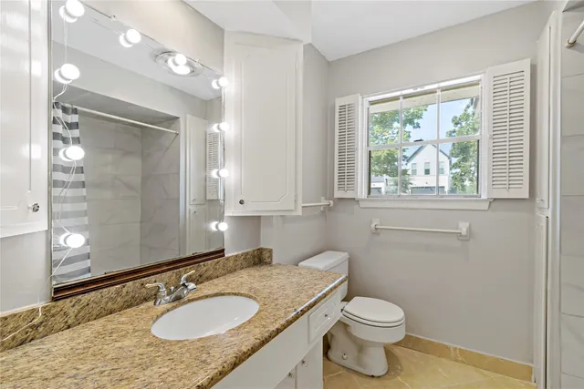 a bathroom with a granite countertop sink toilet and mirror
