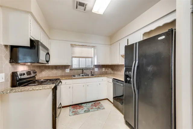 a kitchen with stainless steel appliances granite countertop a refrigerator a sink a stove and white cabinets