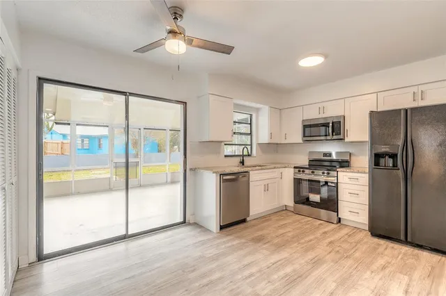 a kitchen with a refrigerator a stove top oven a sink and a large window