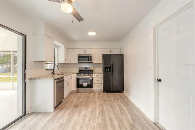 a kitchen with stainless steel appliances granite countertop a refrigerator a stove top oven a sink and dishwasher with wooden floor