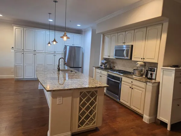 a kitchen with kitchen island granite countertop a sink cabinets and stainless steel appliances
