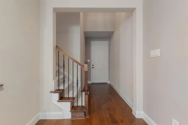 a view of a hallway with wooden floor and staircase