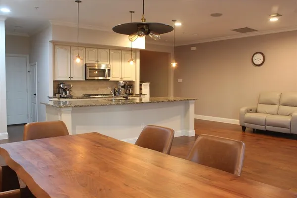 a kitchen with stainless steel appliances granite countertop a sink a stove a dining table and chairs