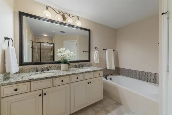 a bathroom with a granite countertop bathtub a double vanity sink and mirror