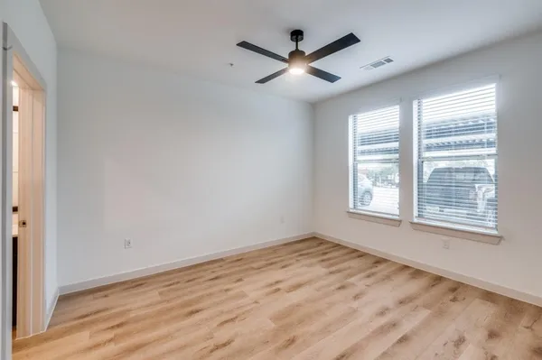 an empty room with wooden floor and windows