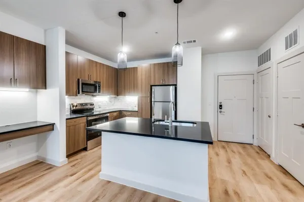 a kitchen with granite countertop a refrigerator a stove a microwave oven a sink dishwasher and white cabinets with wooden floor