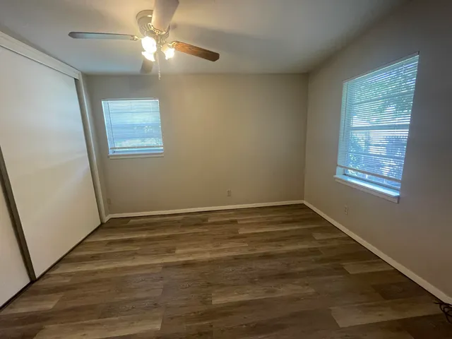 a view of an empty room with wooden floor and a window