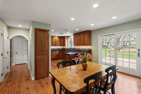 a view of an empty room with wooden floor fireplace and a window