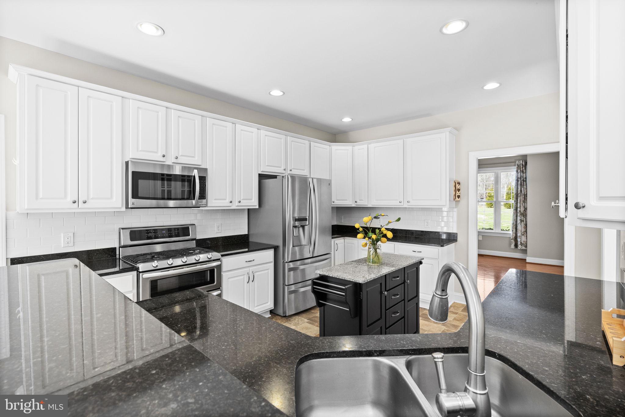 240 Poplar Road Fredericksburg, VA 22406 - Photo 18 of 77 a kitchen with granite countertop a stove a sink a microwave a refrigerator a dining table and chairs with wooden floor