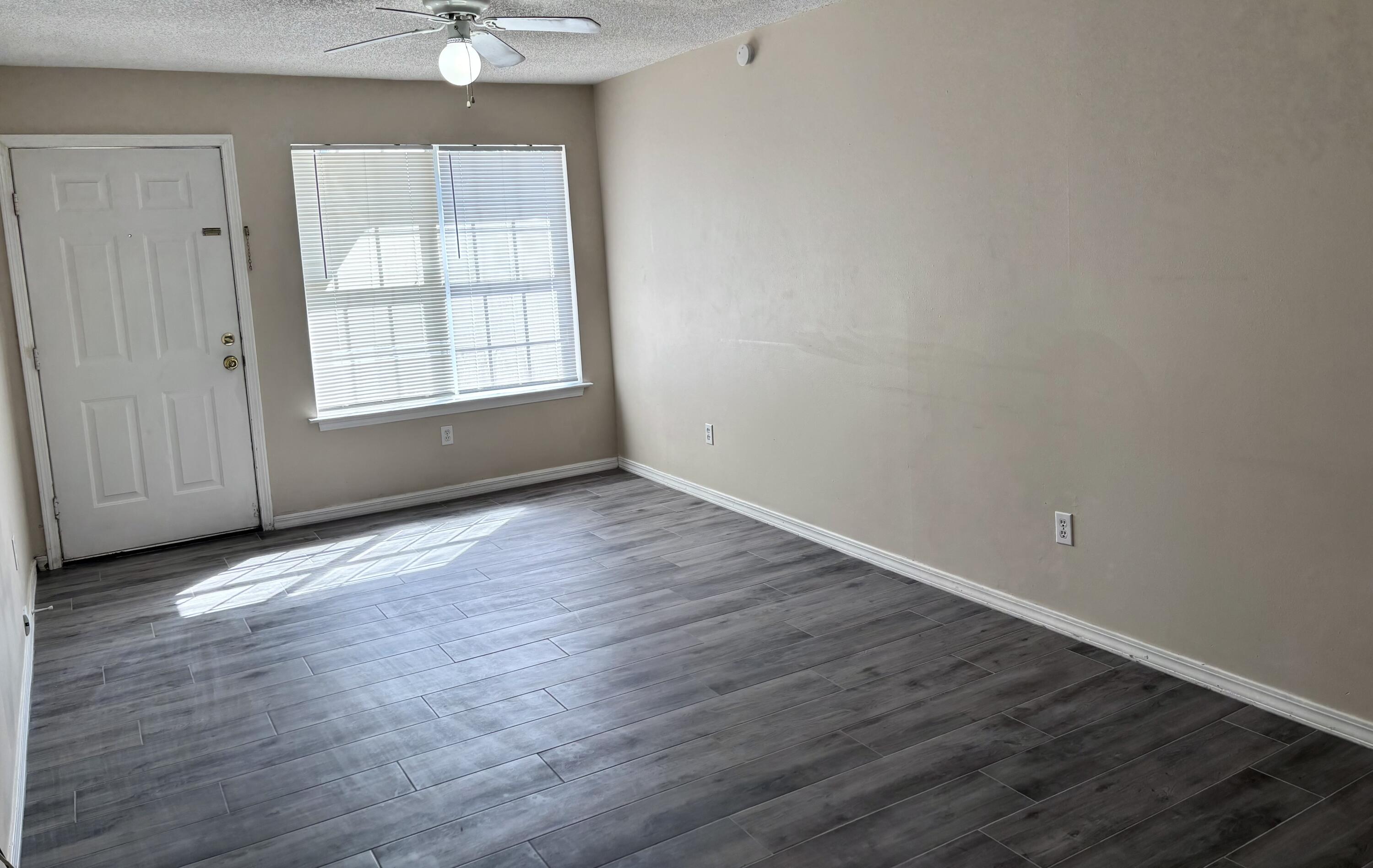 6903 Sea Turtle Circle, Unit B Navarre, FL 32566 - Photo 3 of 10 an empty room with wooden floor chandelier fan and windows
