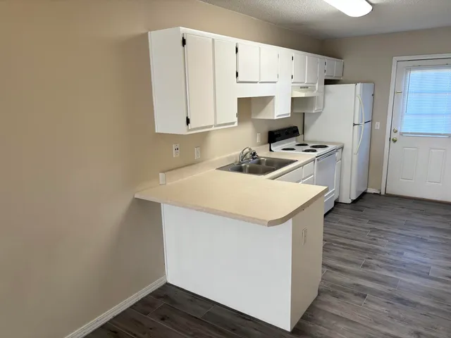 a kitchen with a sink a stove a refrigerator and white cabinets