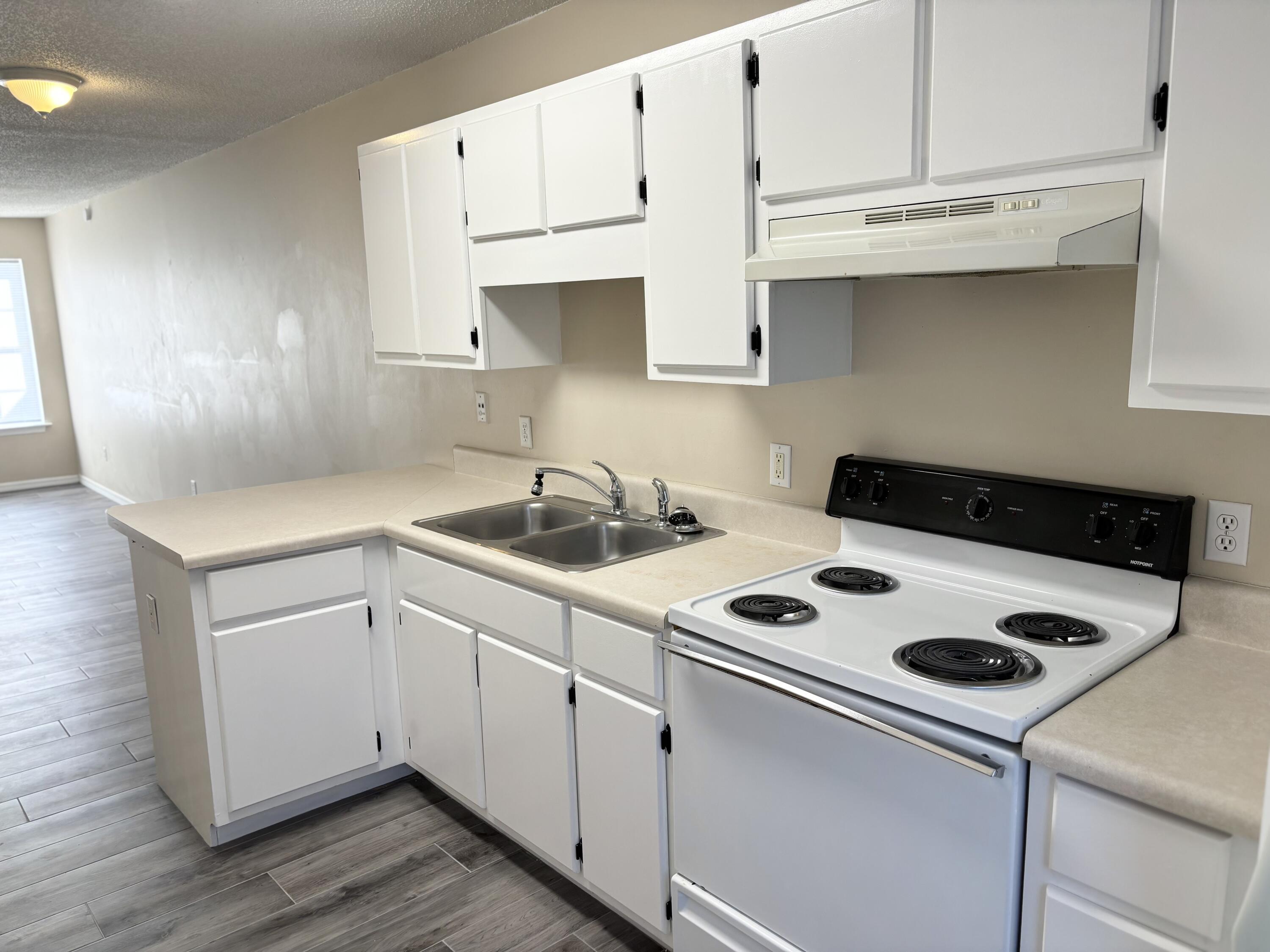 6903 Sea Turtle Circle, Unit B Navarre, FL 32566 - Photo 5 of 10 a kitchen with white cabinets and white appliances