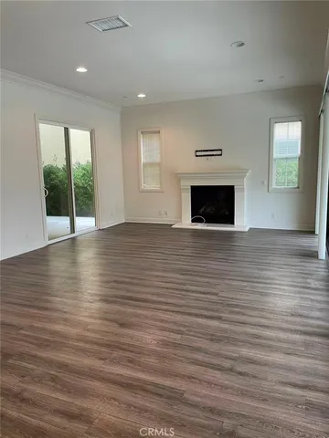 an empty room with wooden floor fireplace and windows