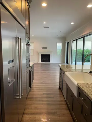 an empty room with wooden floor and a kitchen