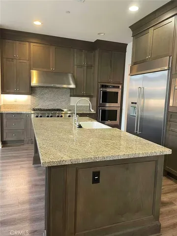 a kitchen with granite countertop a sink a counter top stainless steel appliances and cabinets