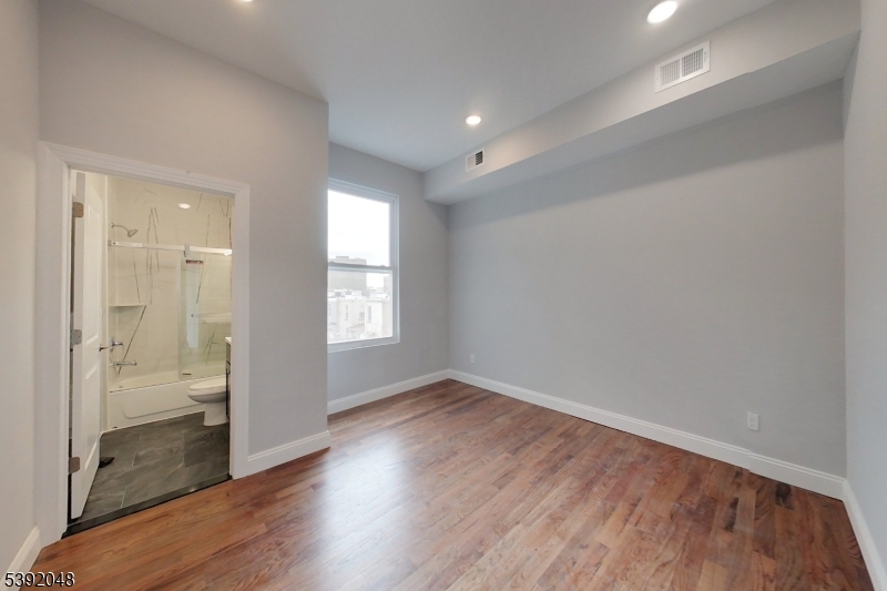 130 45th Street, Unit 2 Union City, NJ 07087 - Photo 11 of 16 wooden floor in an empty room with a window