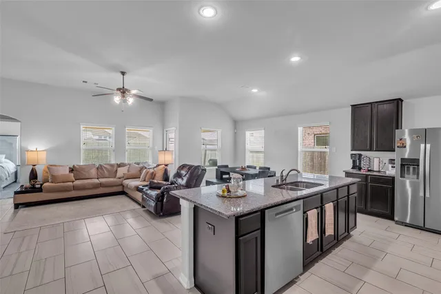 a living room with stainless steel appliances granite countertop a sink dishwasher a stove and a refrigerator with wooden floor