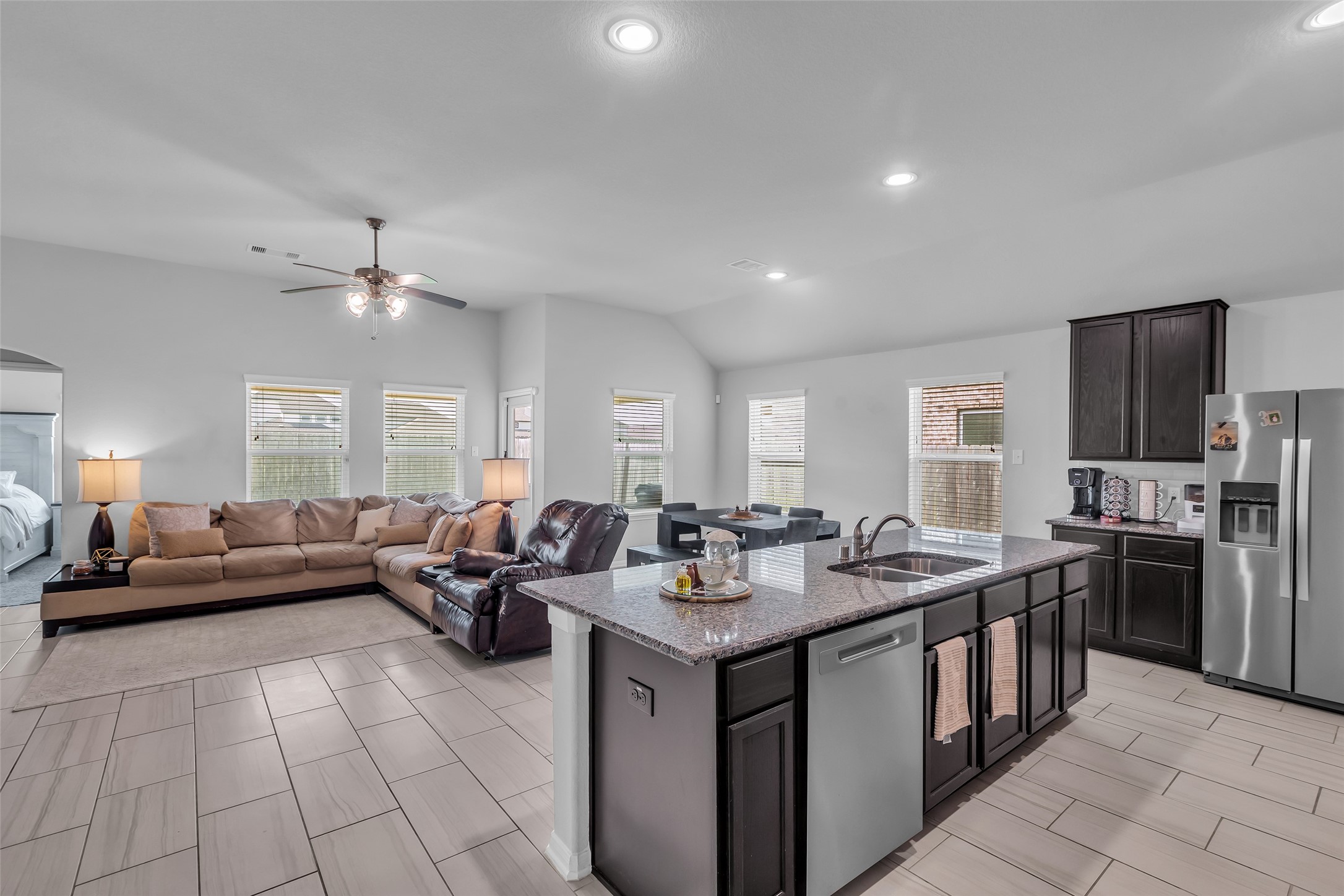 a living room with stainless steel appliances granite countertop a sink dishwasher a stove and a refrigerator with wooden floor