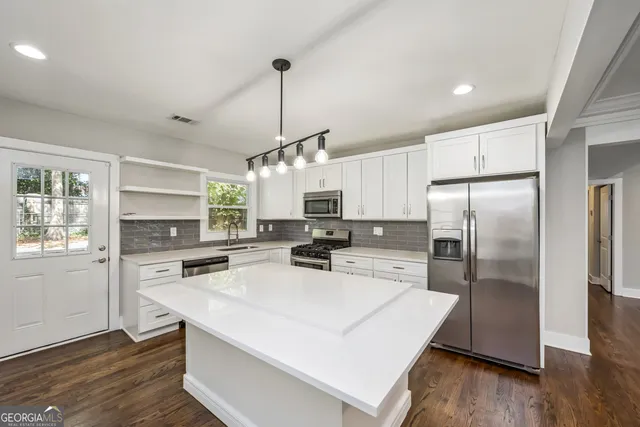 a kitchen with kitchen island a counter top space stainless steel appliances and wooden floor