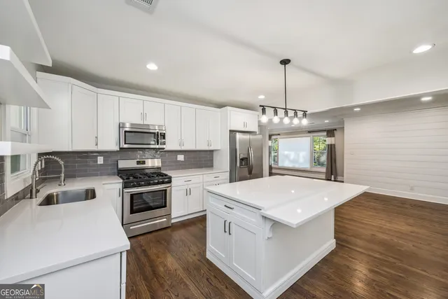 a kitchen that has a sink a stove oven a counter top space and cabinets