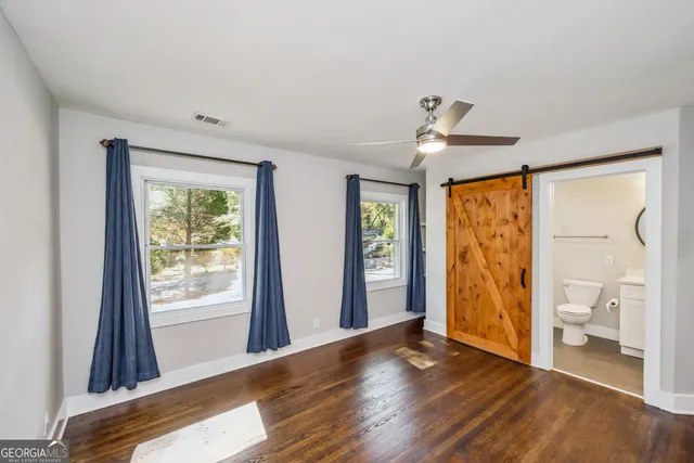 a view of empty room with wooden floor and fan