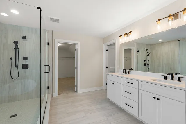 a bathroom with a double vanity sink mirror and shower