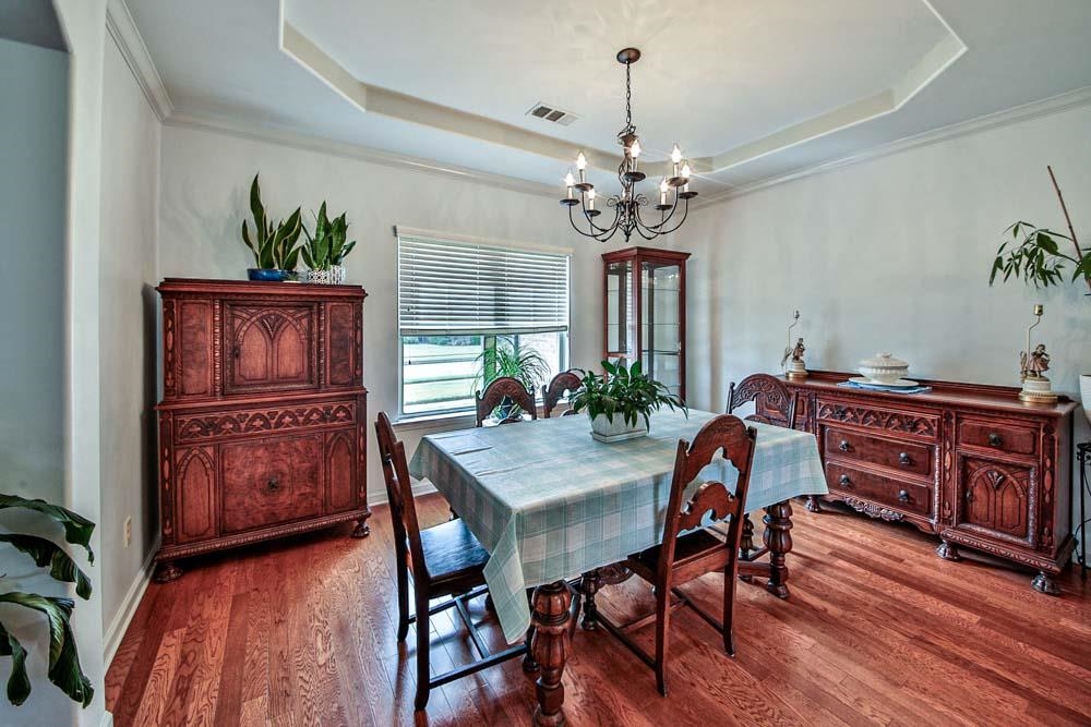 82 Ridgetop Cove Atoka, TN 38004 - Photo 8 of 31 Dining area featuring a raised ceiling, wood finished floors, ornamental molding, and a chandelier