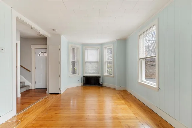 a view of an empty room with wooden floor and a window