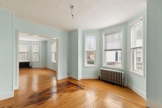 a view of an empty room with window and wooden floor