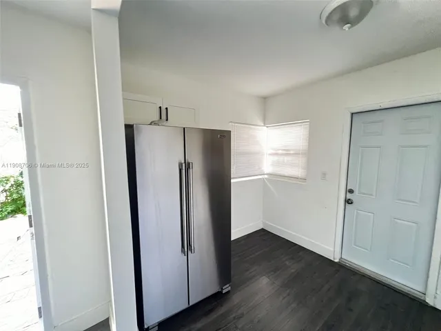a view of a refrigerator in kitchen and an empty room