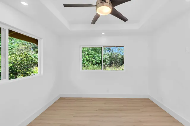 a view of an empty room with wooden floor and window