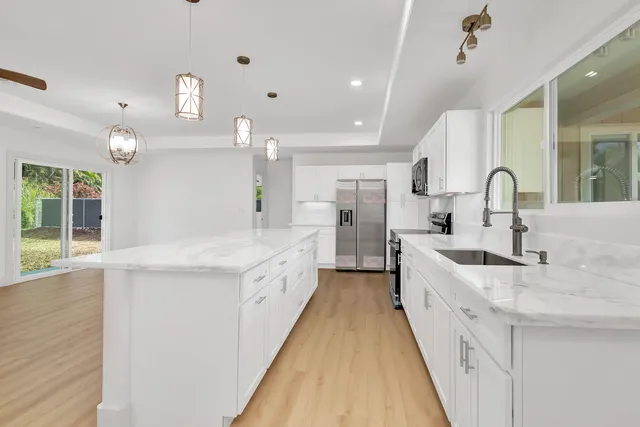 a large white kitchen with a sink and refrigerator
