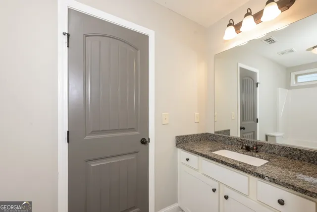 a bathroom with a granite countertop sink and a mirror