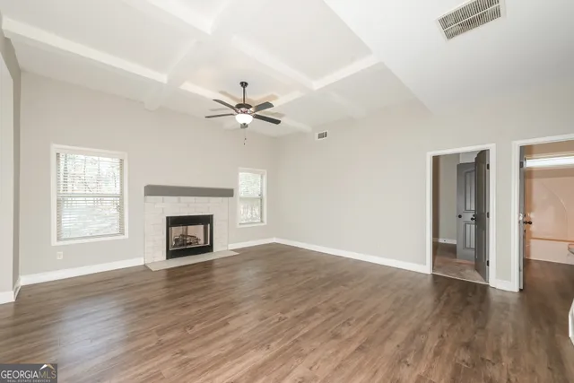 an empty room with wooden floor fireplace and windows