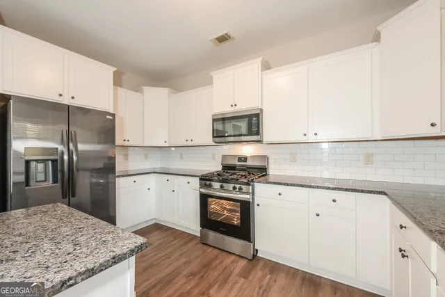 a kitchen with granite countertop white cabinets and stainless steel appliances