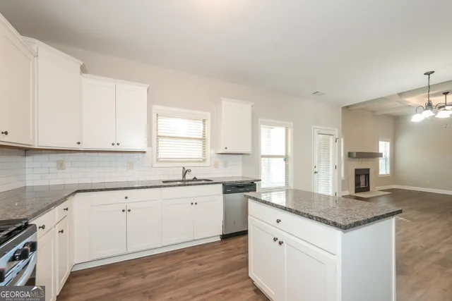 a kitchen with granite countertop white cabinets sink and stainless steel appliances