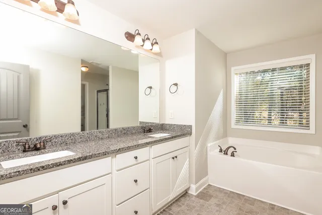 a bathroom with a granite countertop sink mirror and a bath tub