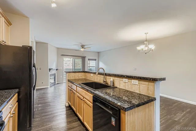 a kitchen with granite countertop a sink dishwasher a refrigerator and a stove with wooden floor