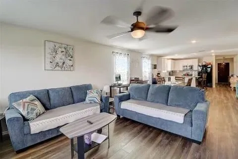 a living room with furniture kitchen view and a wooden floor