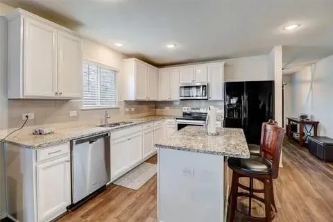 a kitchen with a sink stove cabinets and wooden floor