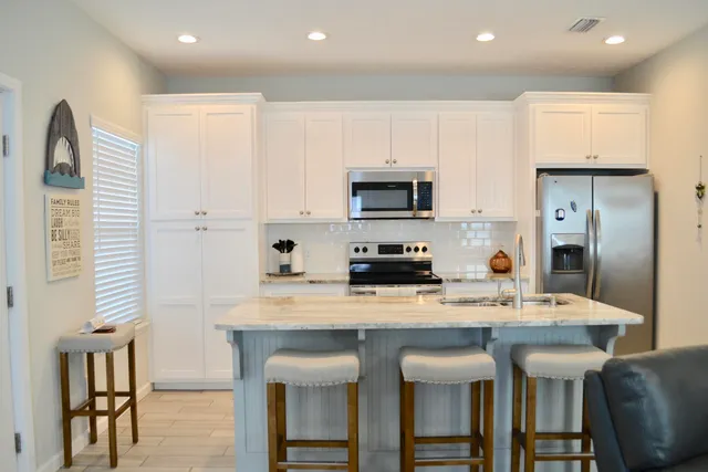 a kitchen with kitchen island granite countertop a table chairs microwave and cabinets