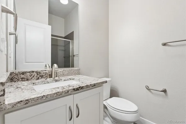 a bathroom with a granite countertop toilet sink and mirror