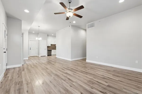 a view of an empty room and kitchen view