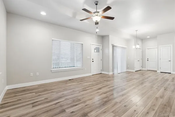 a view of an empty room with a window and wooden floor