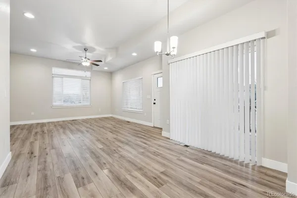 an empty room with wooden floor fan and windows