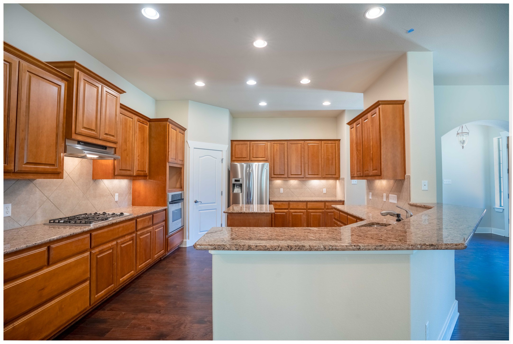 210 Rivulet Lane Austin, TX 78738 - Photo 9 of 28 A well-appointed kitchen features rich wood cabinetry, granite countertops, and modern stainless steel appliances.