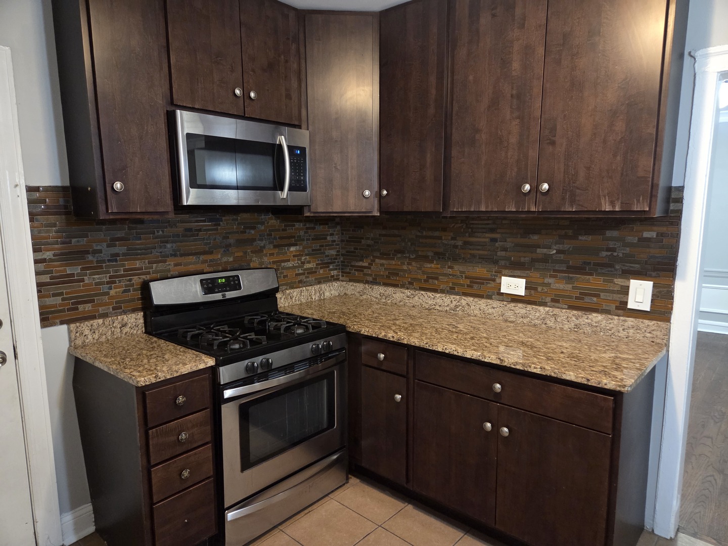 5653 North Spaulding Avenue, Unit 2E Chicago, IL 60659 - Photo 4 of 8 a kitchen with granite countertop stainless steel appliances a stove microwave and sink