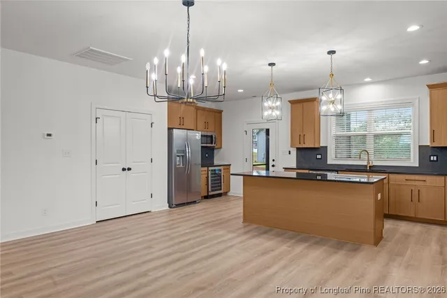 a large kitchen with granite countertop a large counter top a refrigerator and cabinets