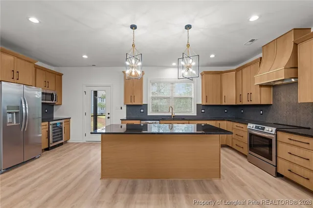 a large kitchen with stainless steel appliances granite countertop a sink a stove and a refrigerator