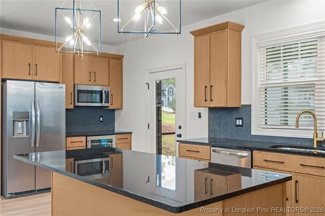 a kitchen with stainless steel appliances granite countertop a sink a stove and a refrigerator